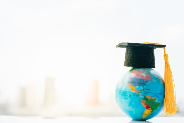 Cappello di graduazione sulla mappa di modello superiore del globo della terra con il fondo della città.