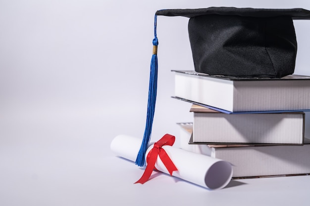 Foto cappello di laurea con libri e diploma sul tavolo contro backgrou bianco