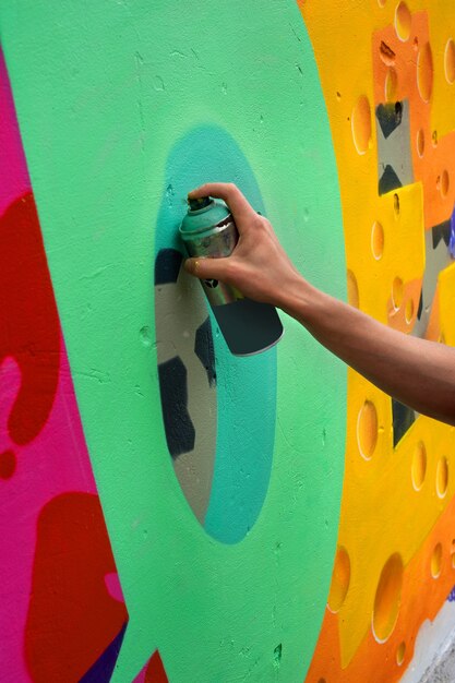 Graffiti artist paints colorful graffiti on a concrete wall. Modern art, urban concept.