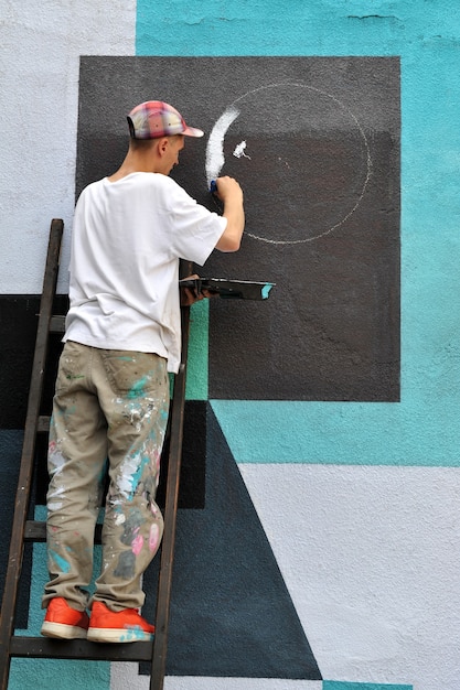 Graffiti artist paints colorful graffiti on a concrete wall.