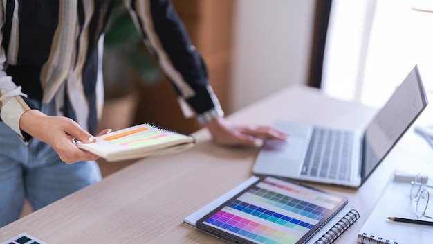 Grafisch ontwerper vrouwen lezen gegevens op laptop en selectiekleur om aan grafisch ontwerp te werken