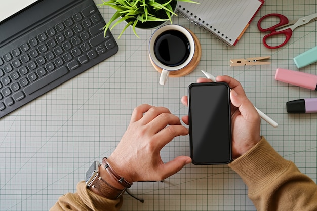 Grafische ontwerper die mobiele slimme telefoon op studio hoogste lijst houdt