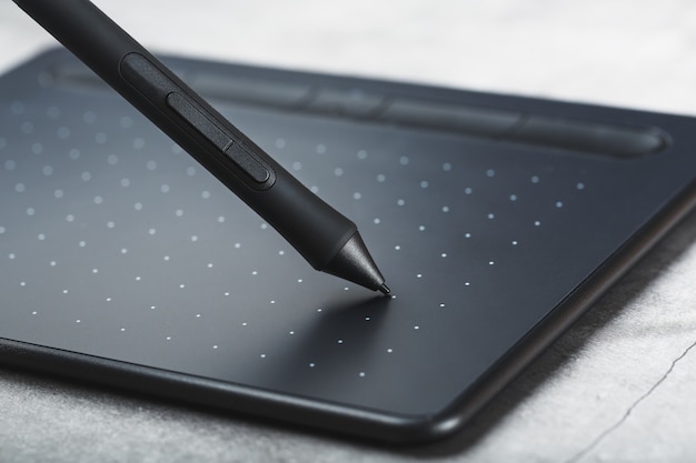 Foto grafische tablet met een pen werkende ontwerper, close-up. gadget voor creativiteit en werk van een fotograaf, illustrator en kunstkunstenaar.