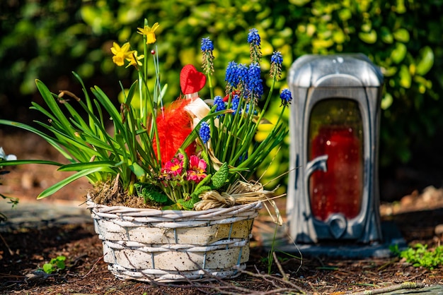 Graflicht met kaars op een graf met bloemen