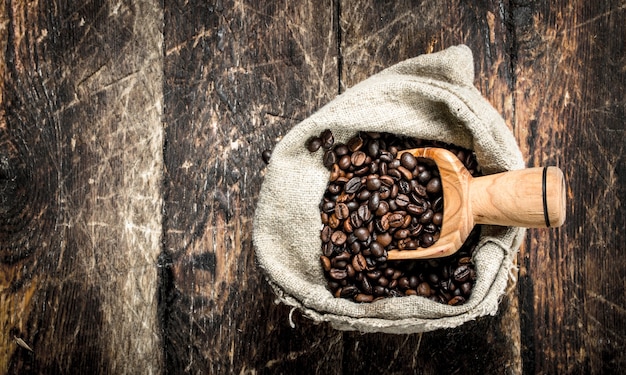 Caffè in grani in un sacchetto. su un tavolo di legno.