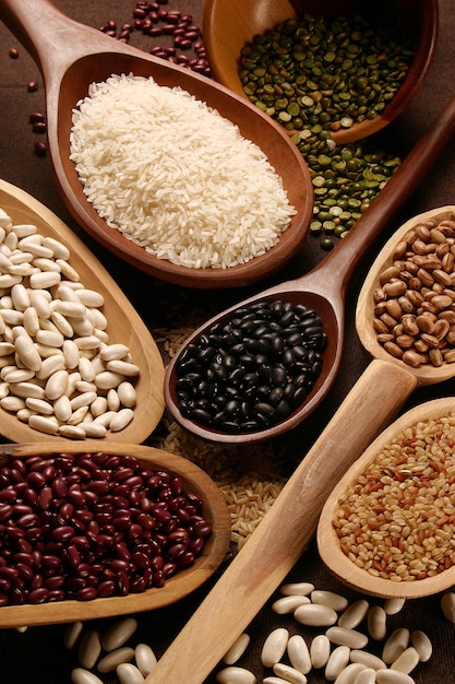 Grain sets peeled, rice and beans in wooden spoon.