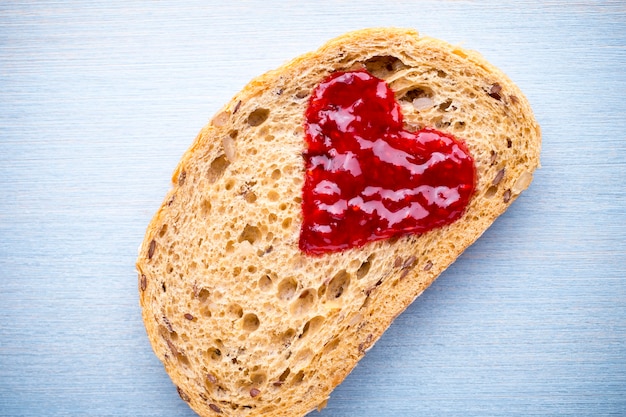 Foto fetta di pane con marmellata a forma di cuore.