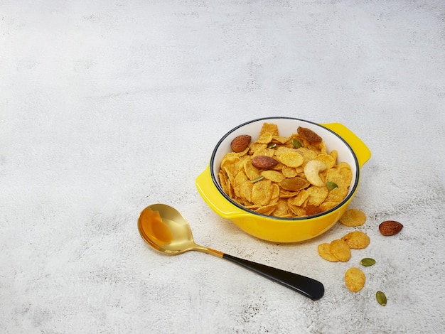 Grains cornflakes in bowl with spoon on white texture background