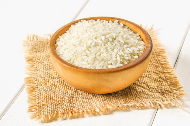 Grains of raw white rice on a white wooden table of boards. Ingredients for cooking.