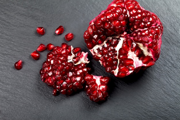 Photo grains of ripe juicy pomegranate on a black background.