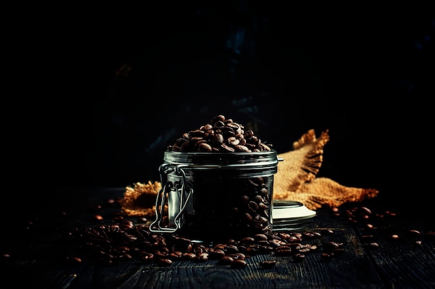 Grains of roasted arabica coffee in a jar on black background selective focus