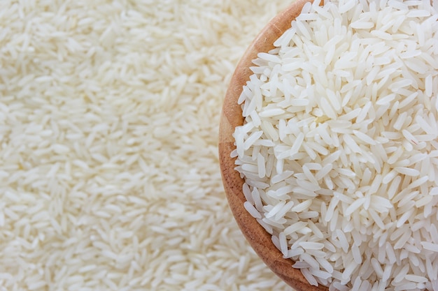 Grains of Thai jasmine rice in wooden bowl on white rice background