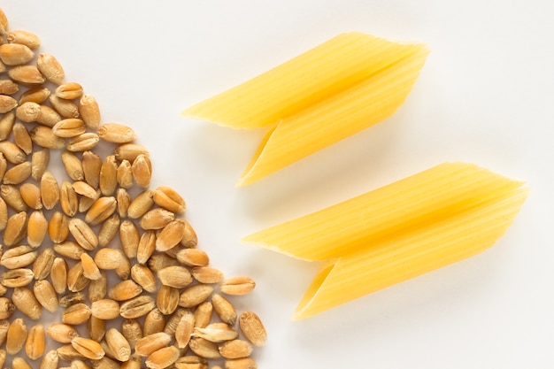 Grains of wheat and pasta in the shape tubes on white