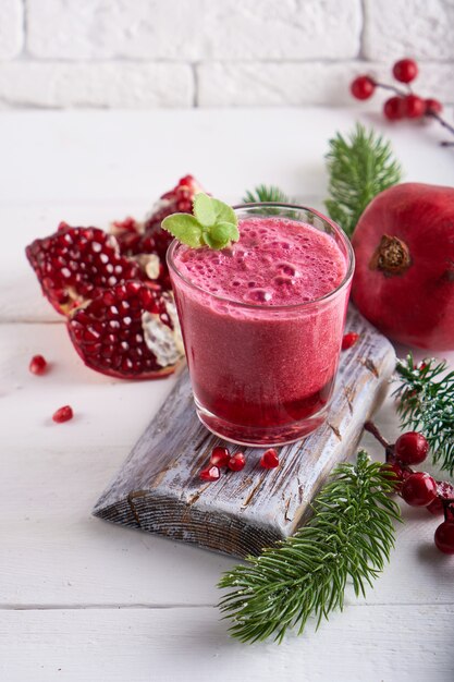 Granaatappel smoothie in een glas met dennentakken en kerstversiering