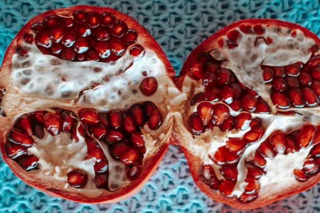 Foto granaatappel verdeeld in twee helften op een blauwe achtergrond van bovenaf gezien concept van winter- en herfstmaanden zoals oktober november en dicember natuur en fruit vitaminen rode kleur