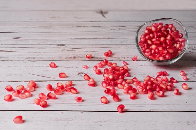 Granaatappelpitjes in een glazen kom en verspreid op een houten tafel