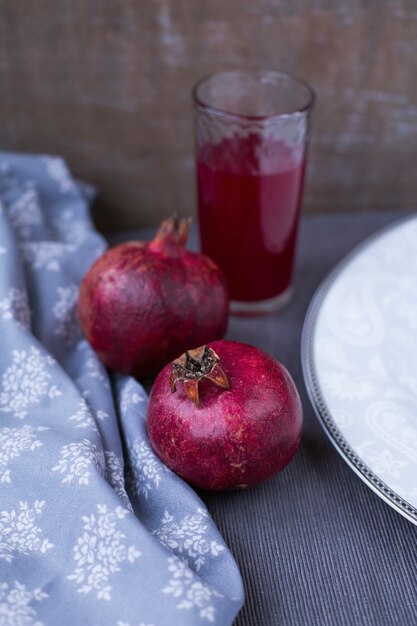 Granaatappels en granaatappelsap in een glas op een grijze tafellaken