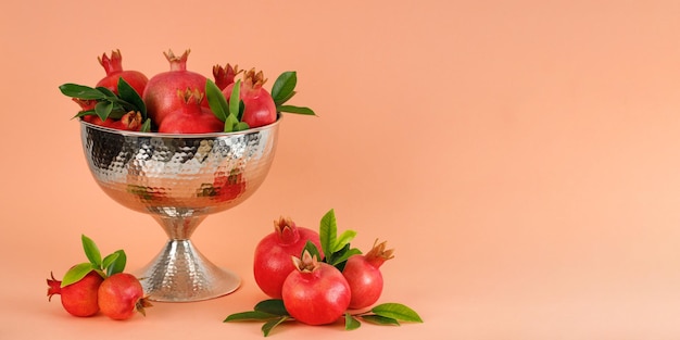 Foto granaatappels in een zilveren kom op een koraalachtergrond rosj hasjana joods nieuwjaar vakantieconcept
