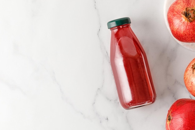 Granaatappelsap in fles met fruit op marmeren achtergrond Vers geperste Vitaminen Bovenaanzicht