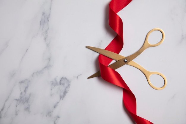 Photo grand opening background gold scissors with red ribbon on a marble background