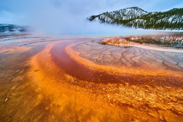 증기로 뒤덮인 푸른 깊이 근처의 놀라운 붉은색과 주황색 층이 있는 Grand Prismatic Spring