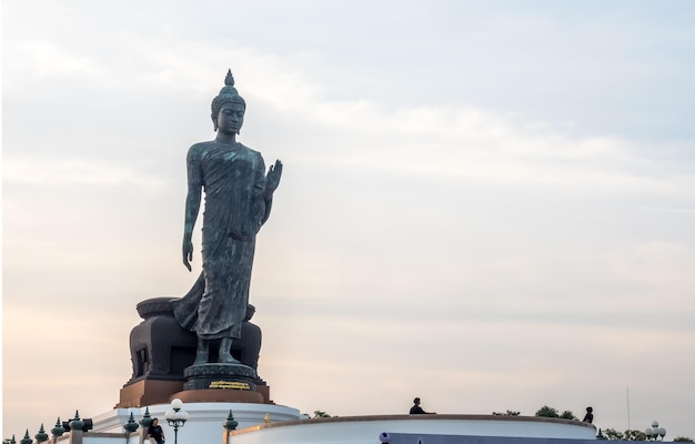 Grand Walking Buddha statue the main statue of Buddhist diocese under twilight sky in Thailand