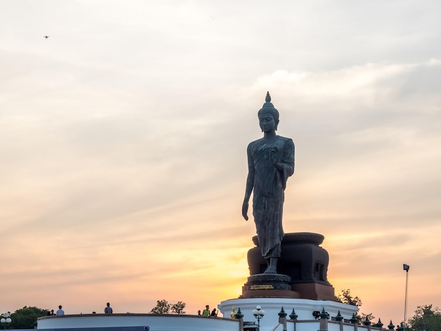 Grand Walking Buddha statue the main statue of Buddhist diocese under twilight sky in Thailand