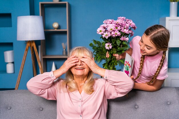 Grandchild presenting flowers to granny at home, happy domestic life moments