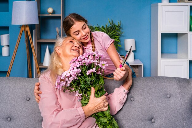 Grandchild presenting flowers to granny at home, happy domestic life moments