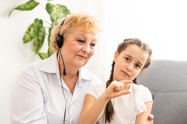 Granddaughter and grandmother listen to mp3 music headphones together smiling.