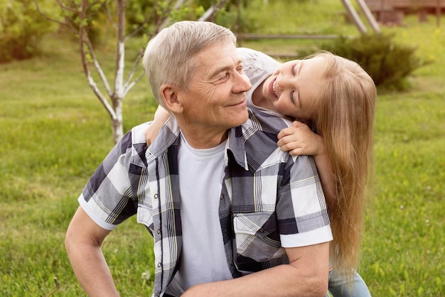 A granddaughter hugs a grandfather with gray hair a happy family a smile on their faces