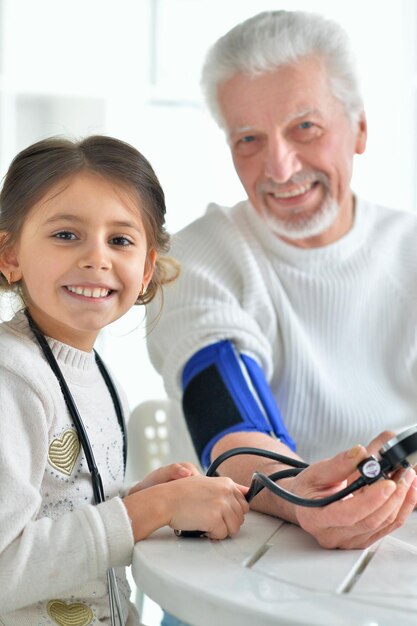 Granddaughter measuring pressure to her grandfather in room