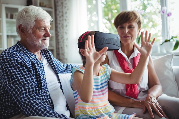Granddaughter using virtual reality headset with her grandparents in living room
