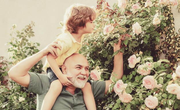 Nonno che porta suo nipote divertendosi nel parco durante l'estate nonno felice che dà