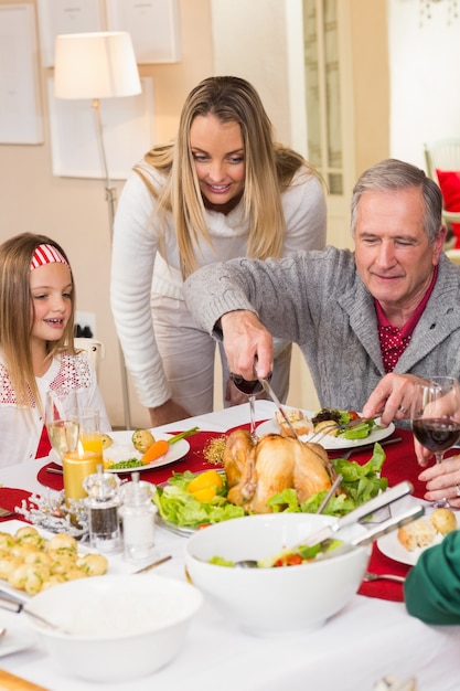 Photo grandfather carving chicken during christmas dinner