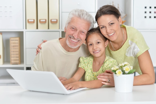Дочь дедушки и внучка вместе используют ноутбук дома