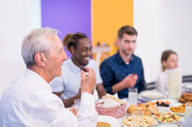 grandfather eating dates with modern multiethnic muslim family while enjoying iftar dinner together during a ramadan feast at home