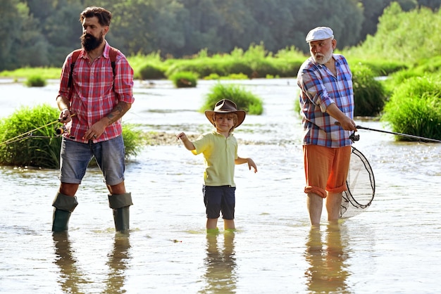 Grandfather father and son are fly fishing on river Anglers Happy fisherman with fishing rod Happy grandfather and grandson are fishing on the river