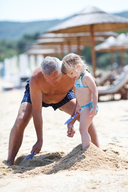 grandfather and granddaughter playing on the beach