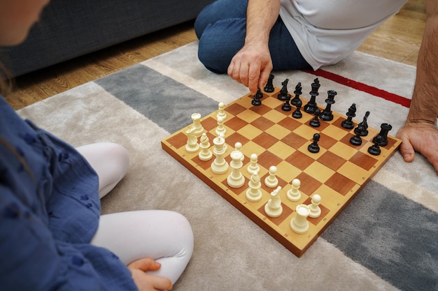 Grandfather and granddaughter playing chess together at home