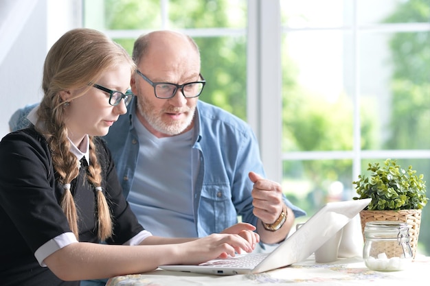 Grandfather and granddaughter using laptop together at home