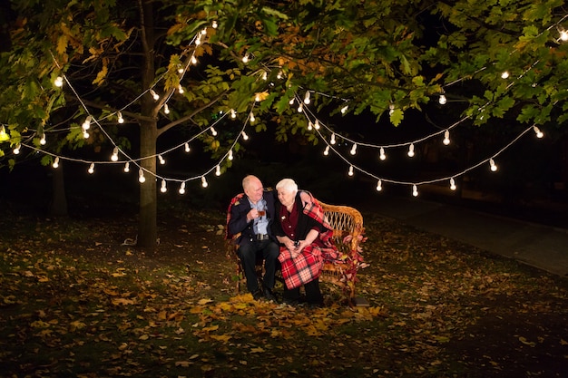 Grandfather and grandmother drinking tea in the park