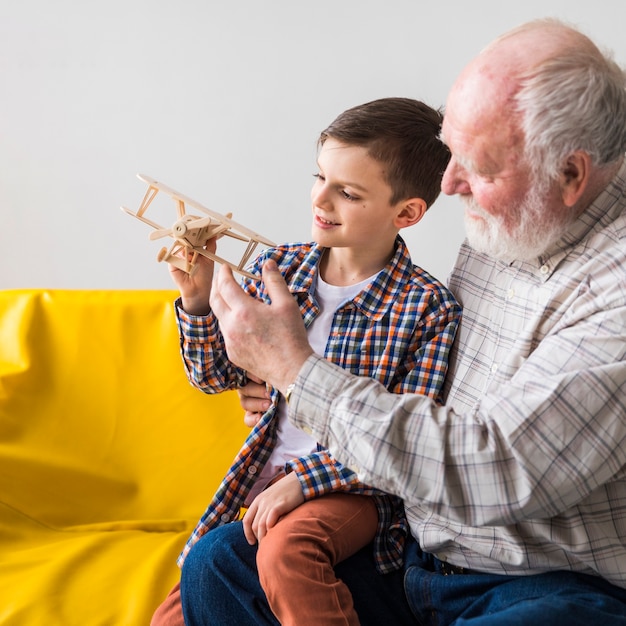 Photo grandfather and grandson playing toy plane