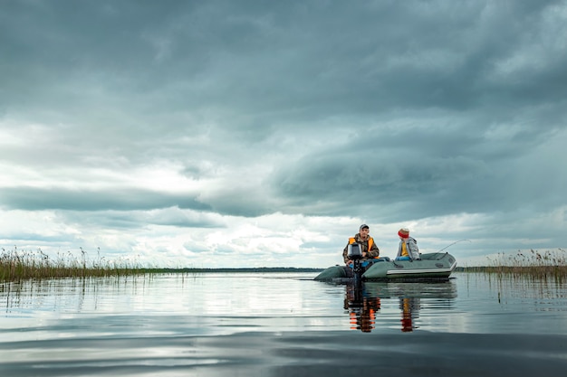 Grandfather and grandson ride a motor boat on the lake.