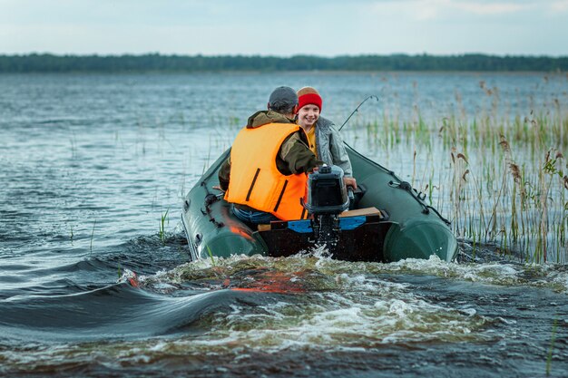 Grandfather and grandson ride a motor boat on the lake.