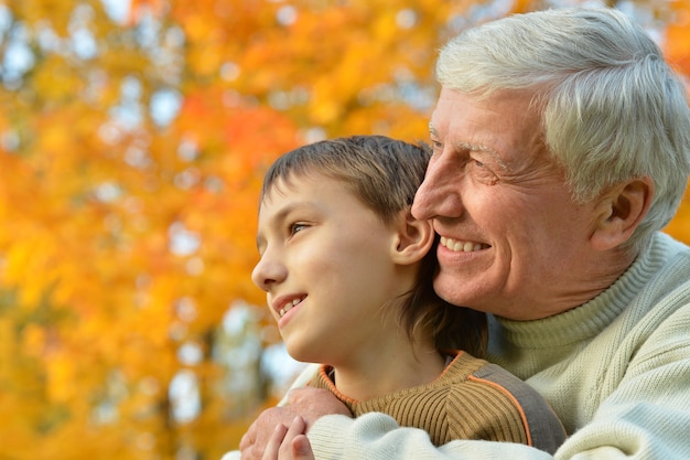 Grandfather and grandson together in autumn park