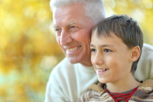 Grandfather and grandson together in autumn park