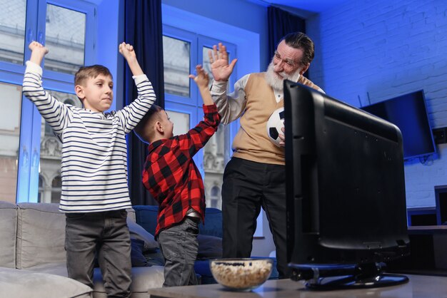 Grandfather and grandson watching television. Grandfather and grandson enjoying at home.