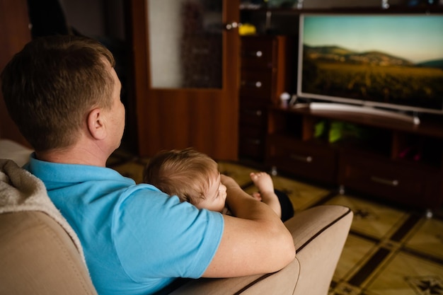 Grandfather and grandson watching TV view from the back watching a movie together at home