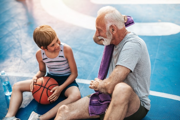 Grandfather and his grandson enjoying together on basketball court.